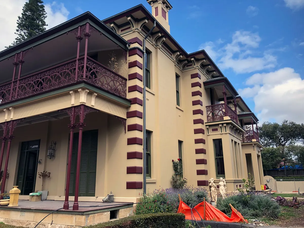 Period villa with a polychrome colour scheme of cream render, claret quoins and green joinery under a blue sky